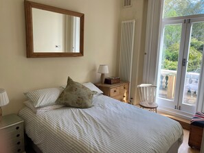 A bedroom with a bed, a dresser, a mirror, a lamp, and a view of the outdoors. - Sleeps 8 max. Beautiful Georgian Grand Square flat with terrace. Victoria 2 mins (London)
