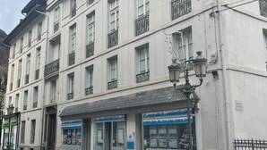 Um edifício com vários andares, fachada plana, diversas janelas e uma vitrine com sinalização.