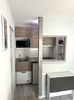 Eine kleine Küche mit Mikrowelle, Spüle und kleinem Kühlschrank.