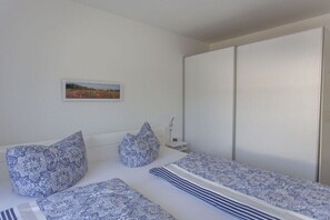 A bedroom with a bed, pillows, a bedside table, a nightstand, and a wardrobe. - Holiday apartment in Baabe with swimming pool (Baabe)