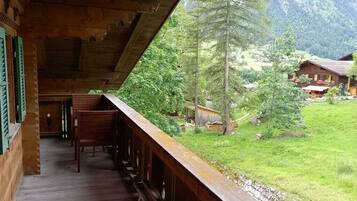 Ein Holzbalkon mit Blick auf ein grünes Tal und bewaldete Berge.