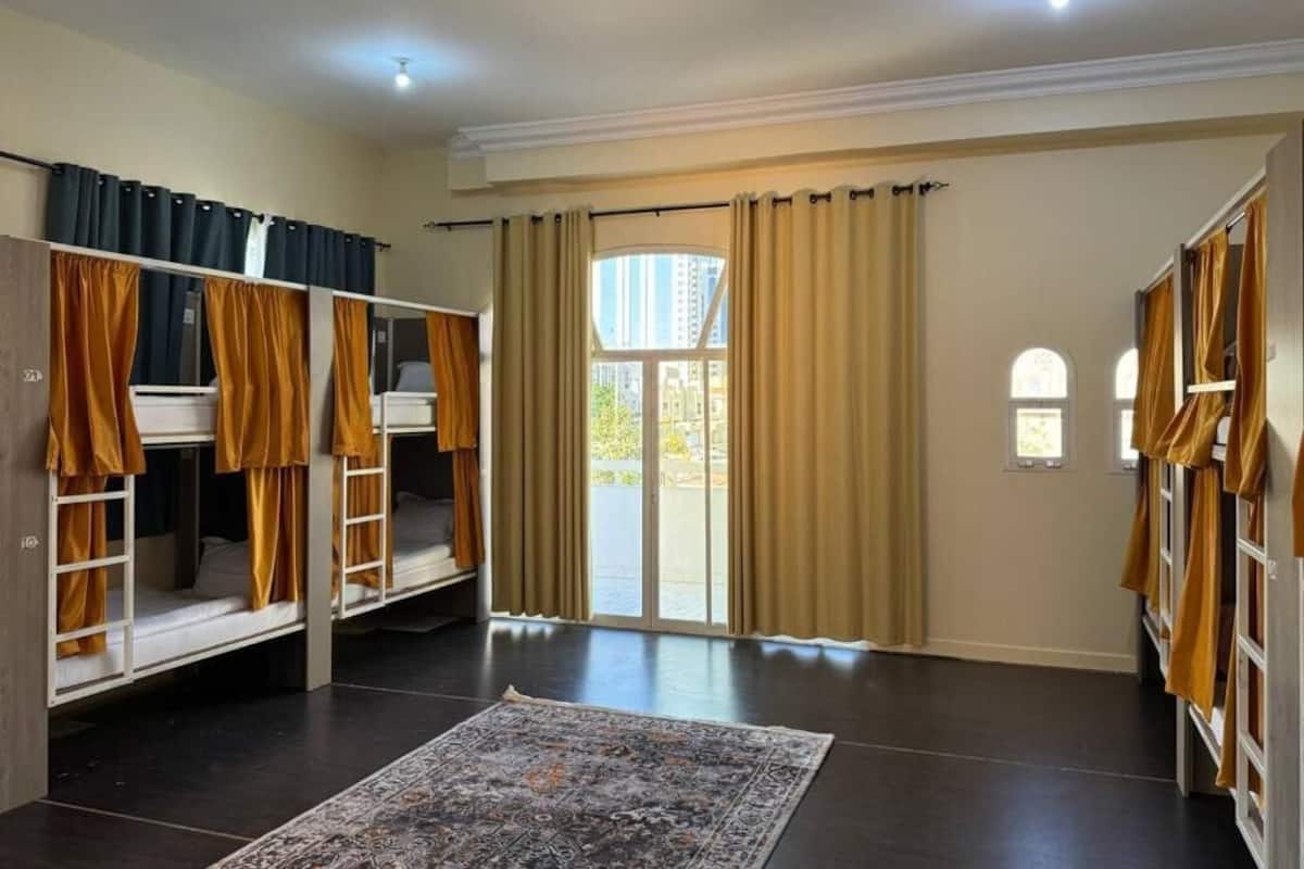 A room with bunk beds, a large rug, and a view through a glass door.