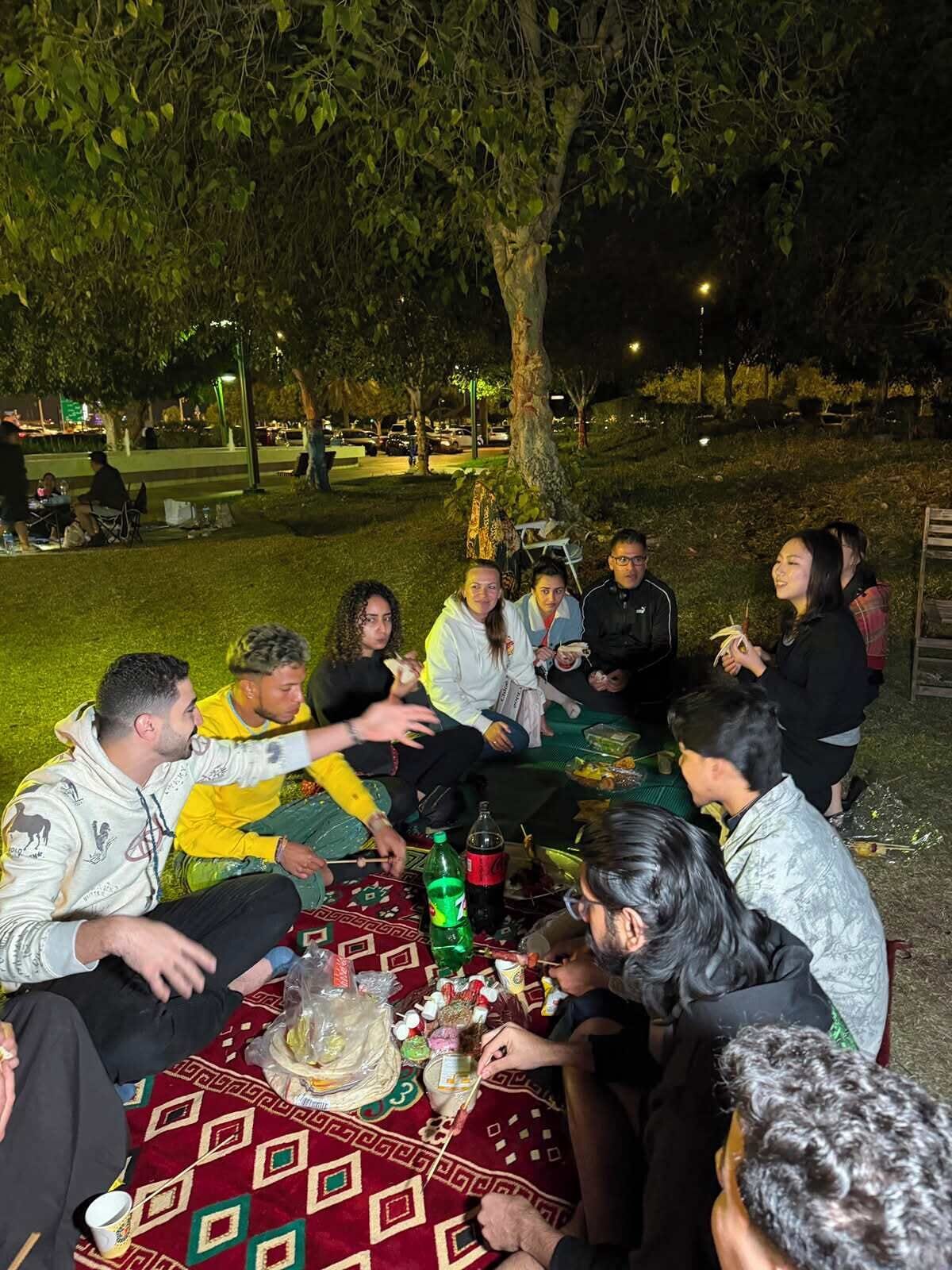Un grup de persones reunides al voltant d'una taula a l'aire lliure de nit.