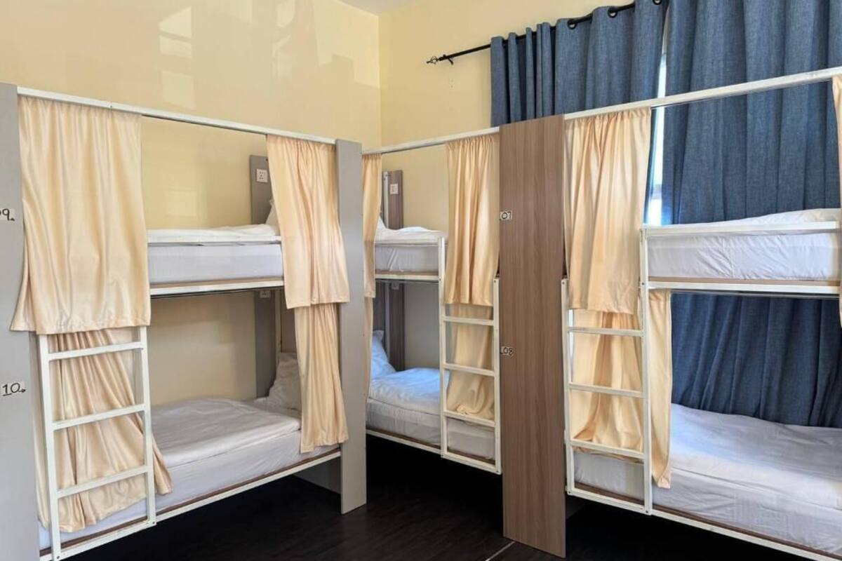 A room with bunk beds, curtains, and a wooden wardrobe.