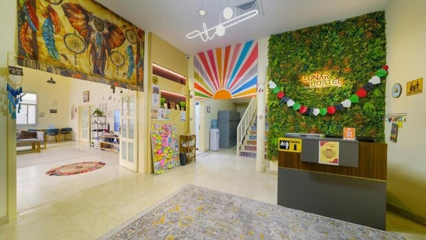 A hotel lobby with a reception desk, a colorful mural, a sun design on the wall, and a check-in counter.