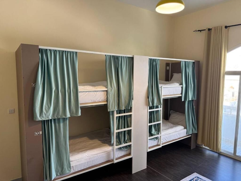 Ein Zimmer mit Etagenbetten, einem Fenster mit Vorhängen und einer Tür.