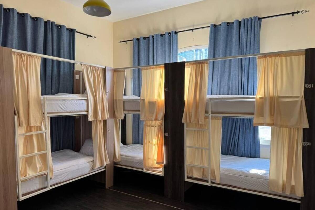 A room with bunk beds, curtains, and a ceiling light fixture.