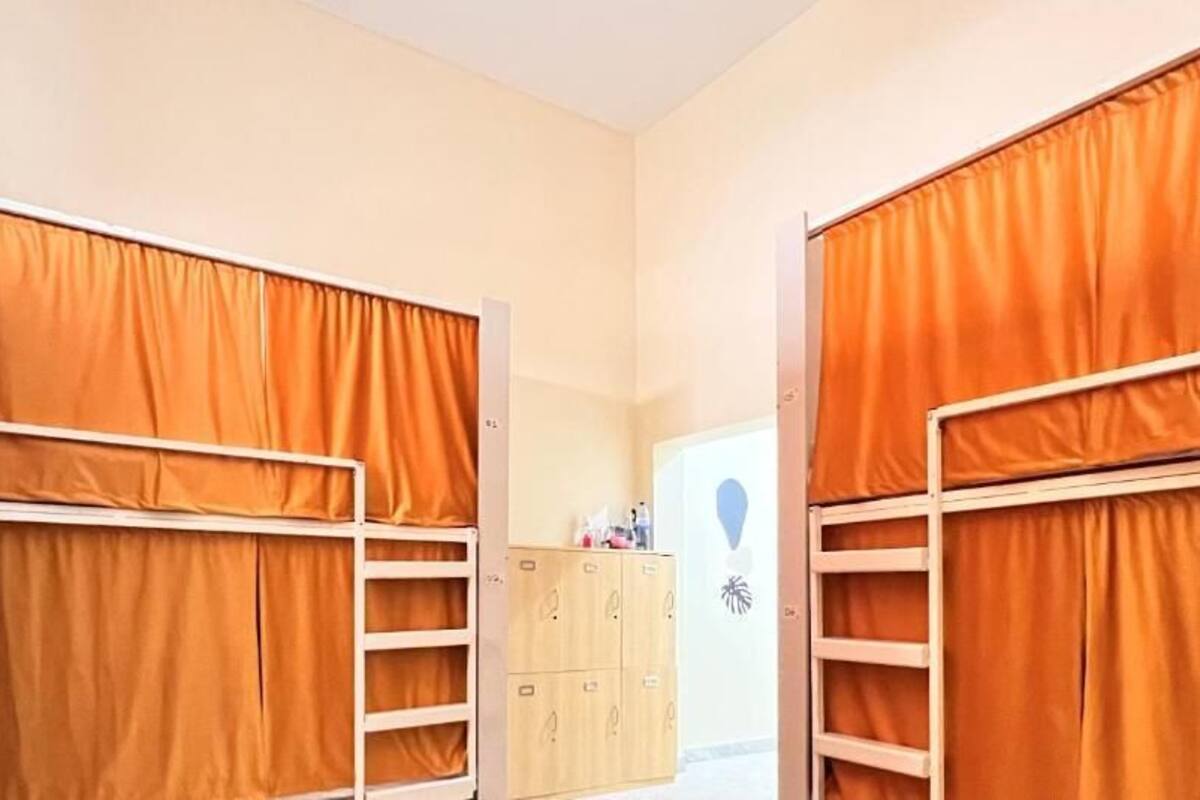 A room with bunk beds, a wardrobe, and a small desk with a chair.