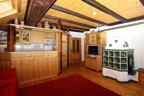 Ein Holzinnenraum mit Küchenzeile, Fernseher und Kamin.