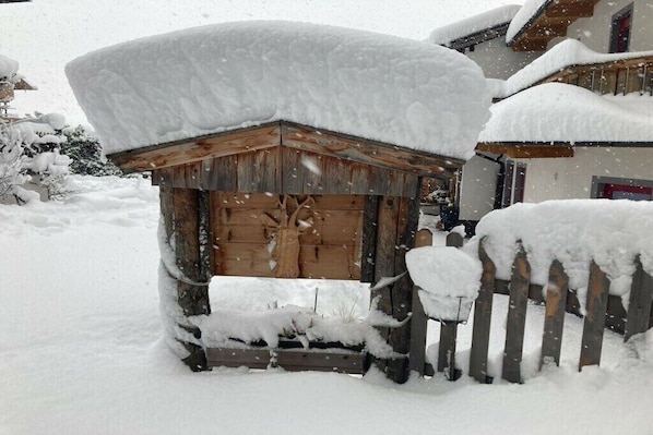 Eine Holzhütte mit verschneitem Dach und einem Holzzaun davor.