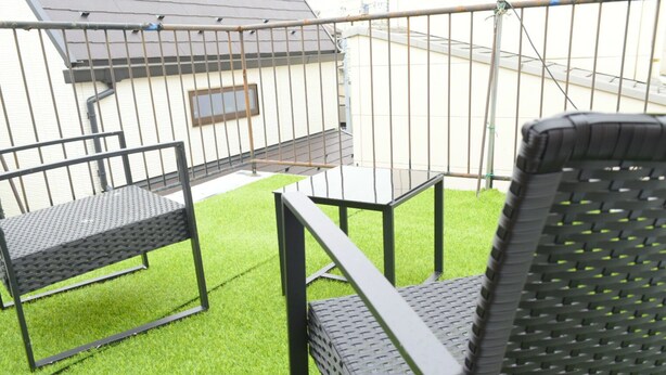 Un espace patio avec une petite table et deux chaises, entouré de gazon synthétique.