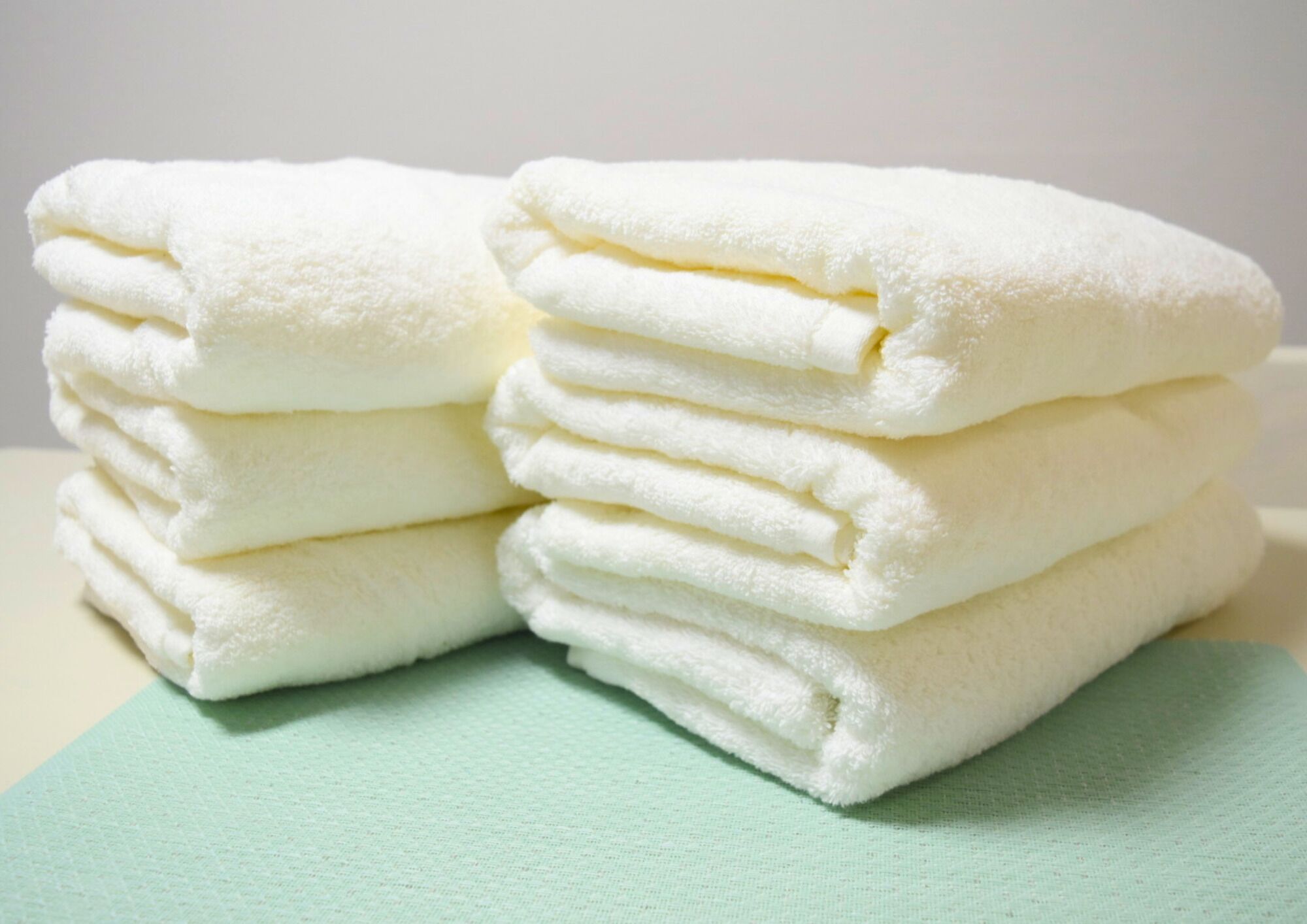 A stack of white towels on a light green surface.