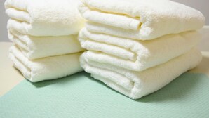 Une pile de serviettes blanches sur une surface vert clair.