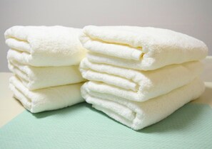 A stack of white towels on a light green surface.
