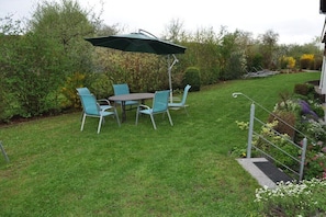 An outdoor patio with a table and chairs, surrounded by a well-maintained lawn and garden. - "Lavender" Family Dietsch (Vestenbergsgreuth)