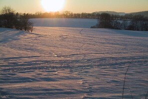 A snowy landscape with a clear sky and the sun setting or rising. - Holiday apartment with 1 bedroom (Schleusingen)
