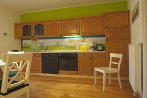 A kitchen with wooden cabinets, a dishwasher, a stove, and a coffee maker. - at the mill stream at the Scherfsmühle (Waldrach)