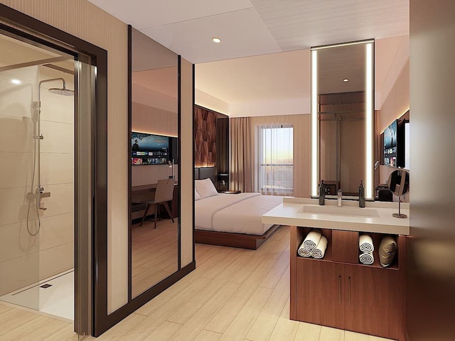 A modern hotel room with a shower, a bed, a TV, and a large mirror.
