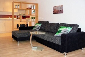 Ein modernes Wohnzimmer mit einer schwarzen Couch, einem Glastisch und einer Holzregalanlage mit Dekoration.