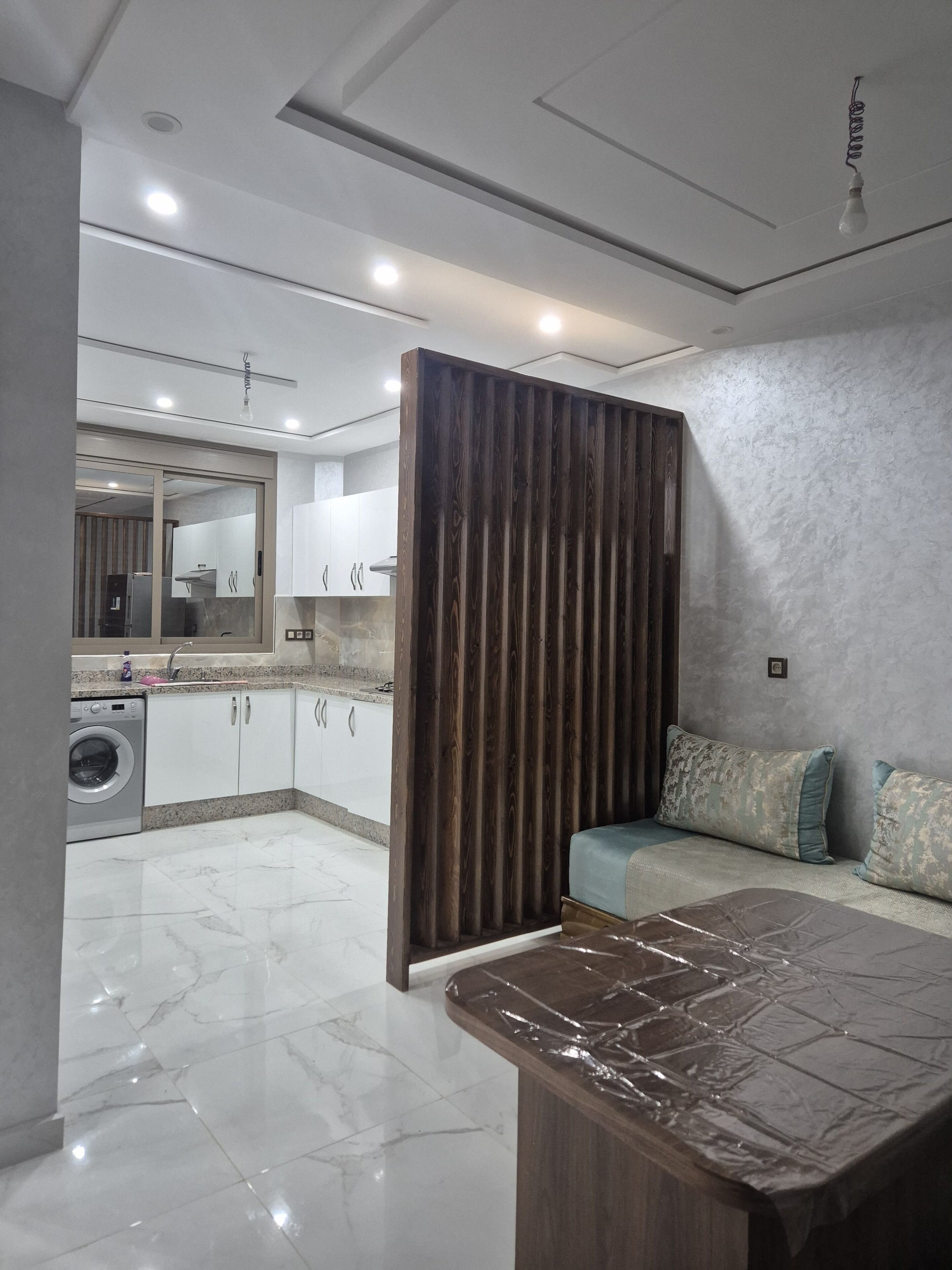 A modern kitchen with white cabinets, a built-in oven, and a washing machine.
