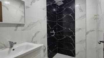 A bathroom with a white sink, a toilet, and a shower area.