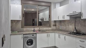 A modern kitchen with a built-in washer, a stainless steel range hood, and a large mirror above the sink.