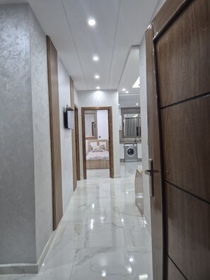 A hallway with a bed, a washing machine, and a wooden wardrobe. - Lovely 2-bedrooms apartment in pleasant Saidia (Saidia)