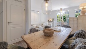 A dining area with a wooden table, woven baskets, and plush chairs. - Beach Love Sylt - Westerland (Westerland)
