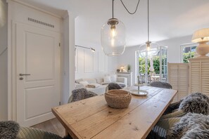 A dining area with a wooden table, woven baskets, and plush chairs. - Beach Love Sylt - Westerland (Westerland)