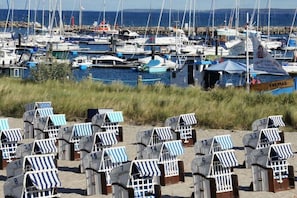 Ein Yachthafen mit zahlreichen Schiffen, Strandkörben mit Nummern und einem Schild mit der Aufschrift 'FREMAD'.