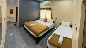 Une chambre d’hôtel avec deux lits, un ventilateur de plafond, un appareil de climatisation, une petite fenêtre avec des rideaux et un miroir au mur.