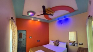 Une chambre à coucher avec un lit, un ventilateur de plafond, un miroir et une petite table.