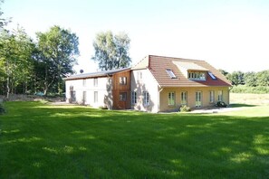 Ein zweistöckiges Haus mit geneigtem Dach, einem sichtbaren Dachboden und einem gepflegten Rasen.