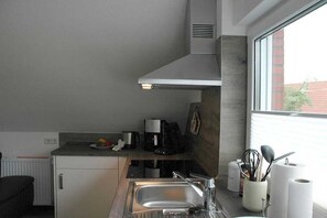 A compact kitchen with a sink, a coffee maker, and a window providing a view of the outside. - Apartment in Norddeich with swimming pool (Norddeich)