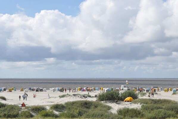 A beach with tents and people, a clear sky, and the sea in the background. - Apartment in Norddeich with swimming pool (Norddeich)