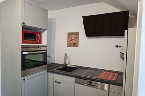 Une cuisine compacte équipée d’un four à micro-ondes, d’un four, d’un évier et d’un lave-vaisselle.