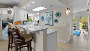 Una cucina moderna con isola centrale, mobili bianchi e piatti decorativi appesi al muro.