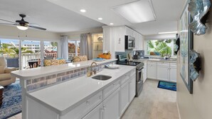 Una cucina moderna con un'isola grande, mobili bianchi e vista all'esterno.