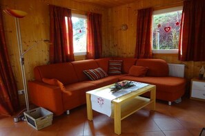 Ein gemütliches Holzhaus mit einer Couch, einem Tisch mit weißem Tuch und einer Heizung.