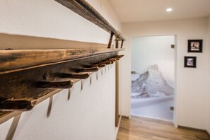 Ein Korridor mit einer hölzernen Bank, einer Tür mit einem Bergmotiv und einem gerahmten Bild an der Wand.
