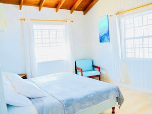 Ein Schlafzimmer mit einem Bett, einem Sessel und einem Fenster.