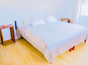 Ein Bett mit weißer Bettwäsche, Nachttische aus Holz und eine Uhr auf einem Nachttisch.