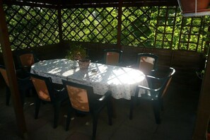 Eine Terrasse im Freien mit einem runden Tisch und Stühlen, umgeben von einem Holzzimmerfenster.