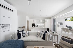 A modern living room with a sofa, a coffee table, and a dining area with chairs. - #4 Porter's Place - by ZenBreak (Porters)