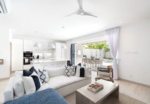 Ein modernes Wohnzimmer mit Sofa, Couchtisch und Blick auf die Küche und den Essbereich.