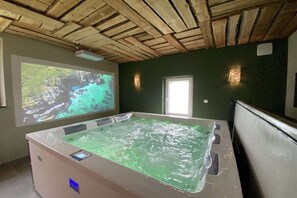 Un cuarto de spa con una bañera grande, una pantalla de proyección y un techo de madera.