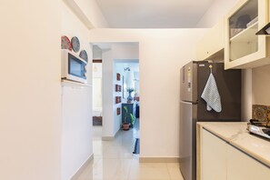 A narrow kitchen with a microwave, refrigerator, and cabinets.