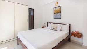 A bedroom with a bed, a nightstand, a wall-mounted shelf, a door, and a ceiling fan.