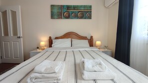 A neatly made bed with two pillows, two bedside lamps, and two folded towels on the bed. - Beautiful House In Fethiye (Fethiye)