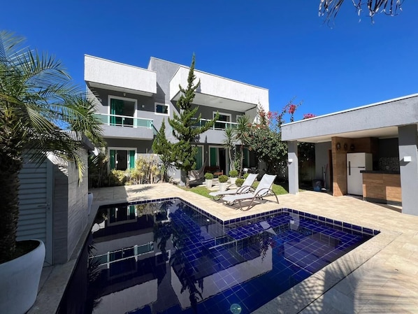 Une maison moderne dotée d’une piscine, de mobilier d’extérieur et d’un jardin bien entretenu.